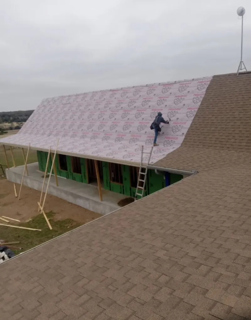 Worker preparing underlayment for a metal roof installation in Glencoe